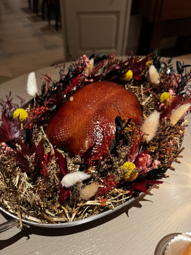 Roast duck presented among dried flowers before serving
