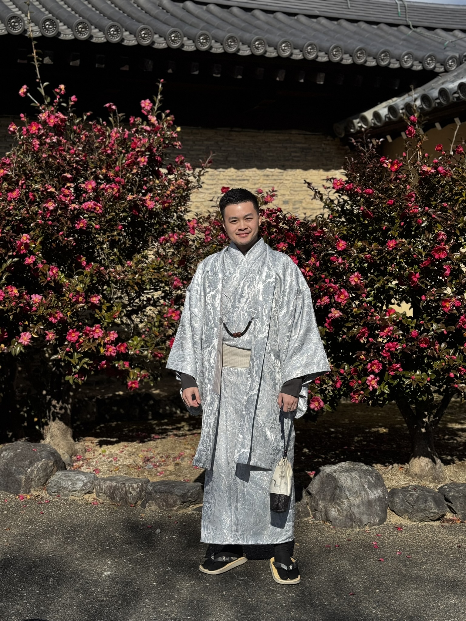 Portrait wearing a silver kimono between flowering bushes in Kyoto