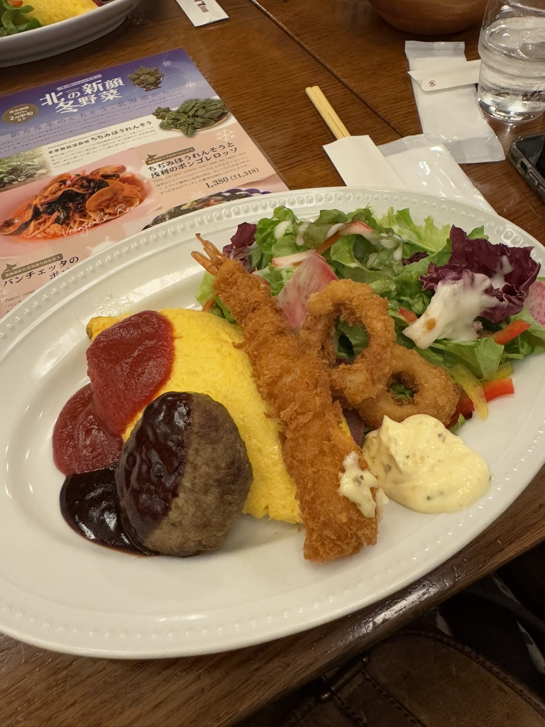 Lunch plate with omurice, fried seafood, salad, and hamburger patty