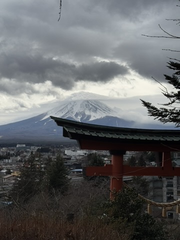 Mt. Fuji seen near a red pagoda roof under cloudy sky