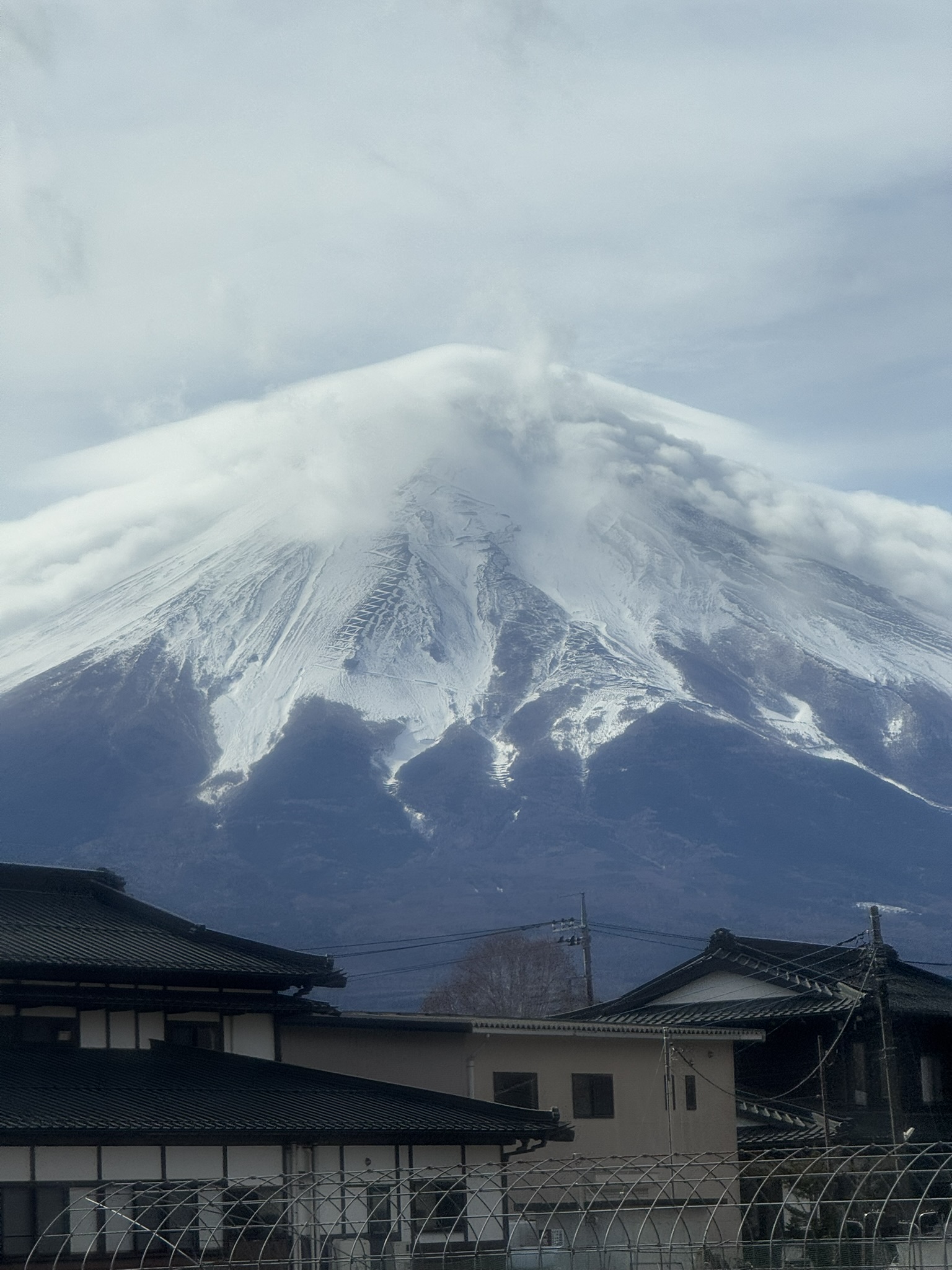 Close view of snowy Mt. Fuji with clouds around the peak